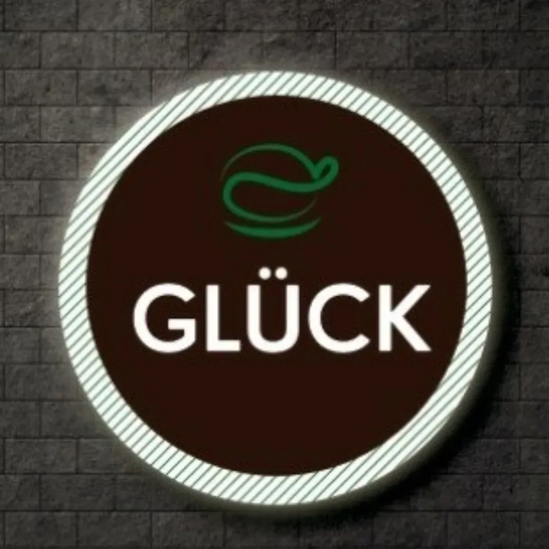 Aviso luminoso con el logo de Glück sobre una pared de ladrillo oscuro